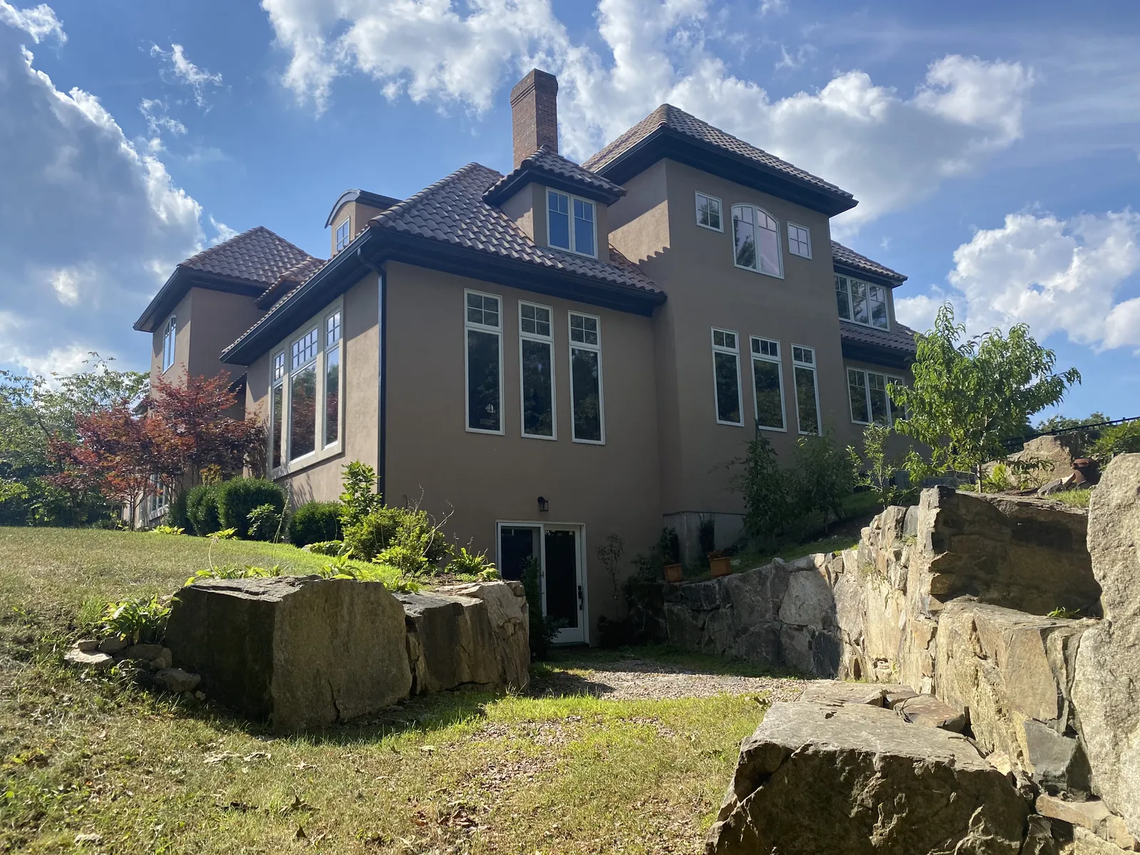 Large stucco home with dark gutter system installed around the roofline