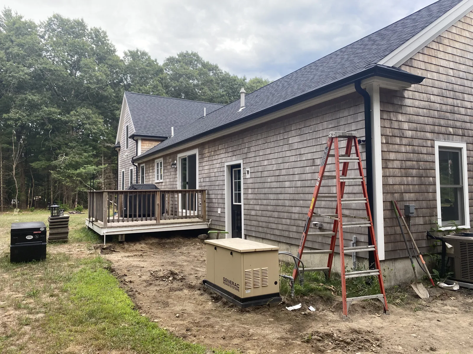 Side yard view of a cedar home with newly installed black gutter system