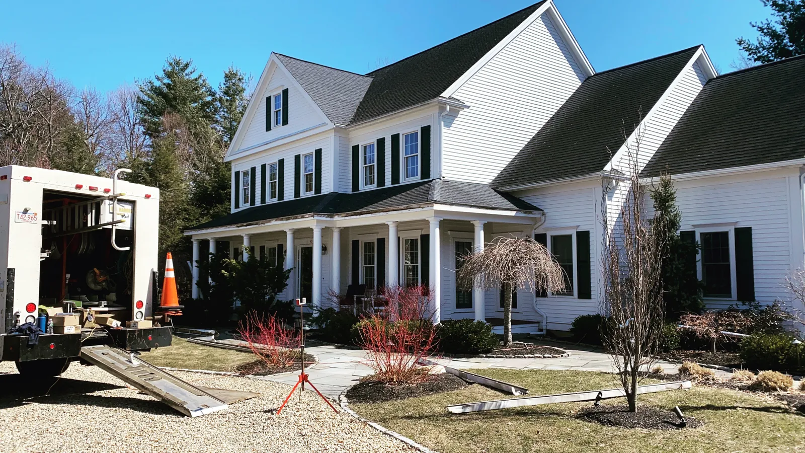 Large white colonial home with B.A. Harris work truck parked during gutter work