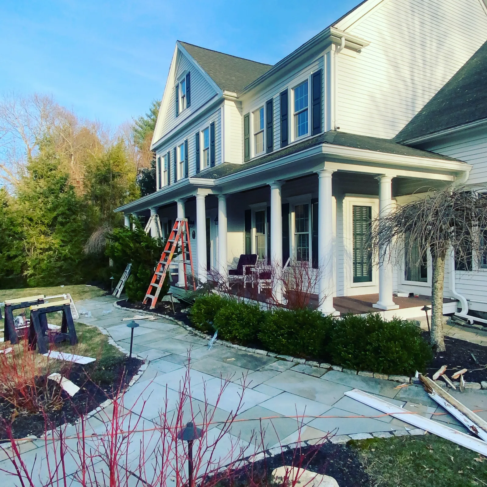 Front walk view of a large colonial home with gutter installation in progress